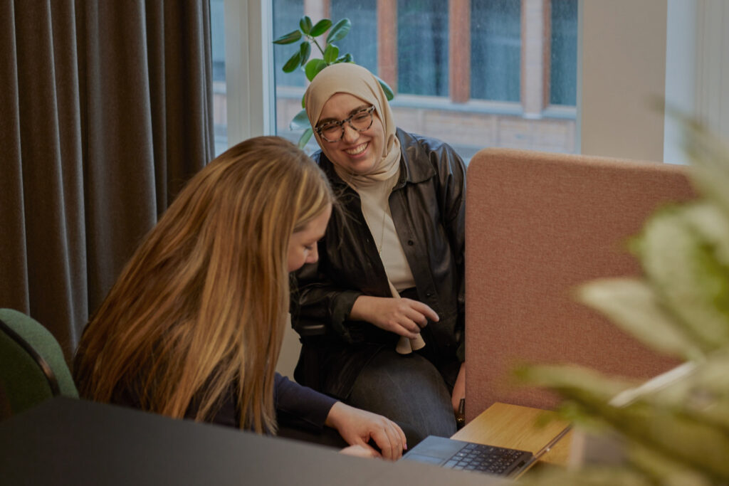 Två glada Hemsömedarbetare arbetar tillsammans i kontorslandskap