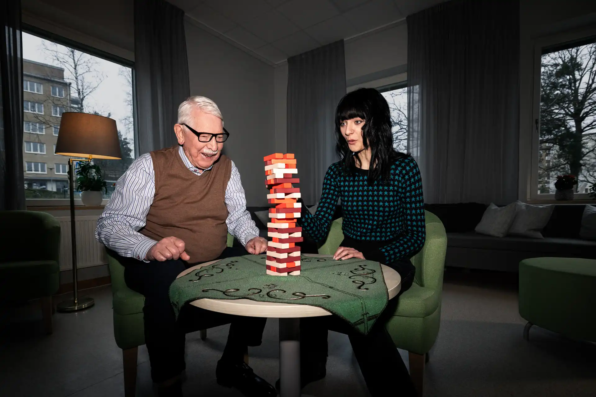 Morfar spelar spel med sitt barnbarn i sitt ombonade rum på äldreboendet.